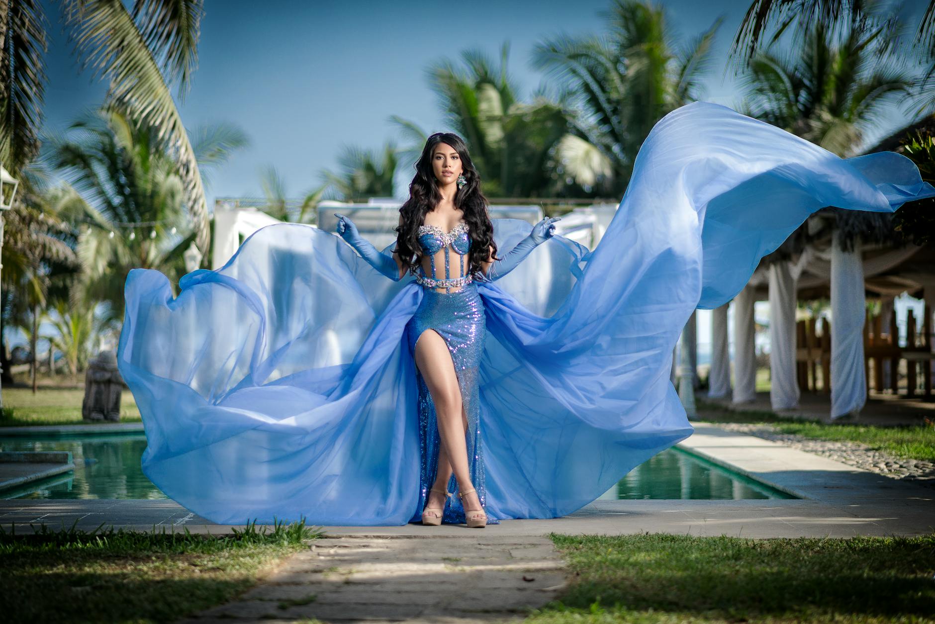 woman in a blue evening dress standing by the pool